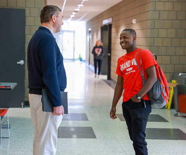 A Grand View student and professor chatting outside the classroom.
